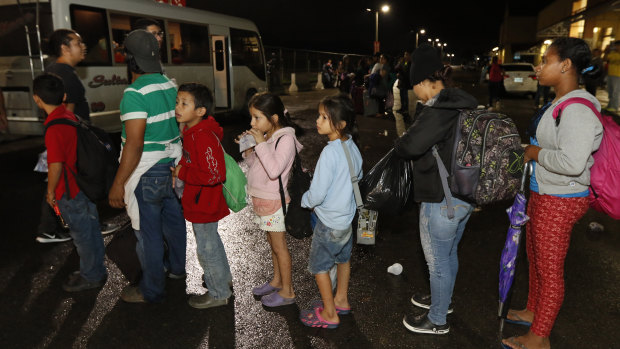 Migrants hoping to reach the United States wait in line to board a bus toward Honduras' border with Guatemala.