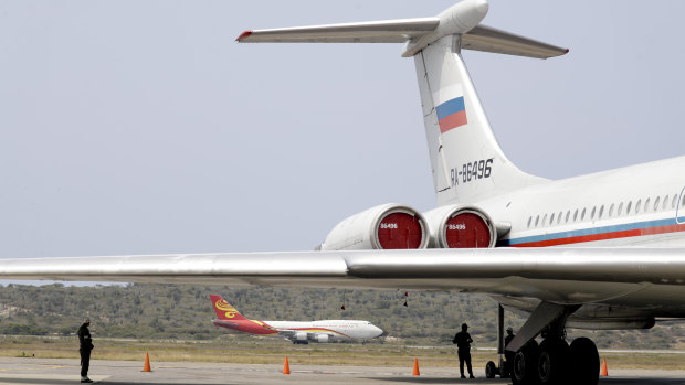 A Chinese plane lands near a Russian plane parked on the tarmac at the Simon Bolivar International Airport in Maiquetia, near Caracas, Venezuela.