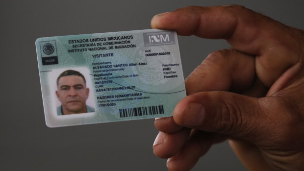 A Honduran migrant shows his temporary Mexican humanitarian visa at the border between Mexico and Guatemala, where many migrants are waiting for humanitarian visa applications to be processed.