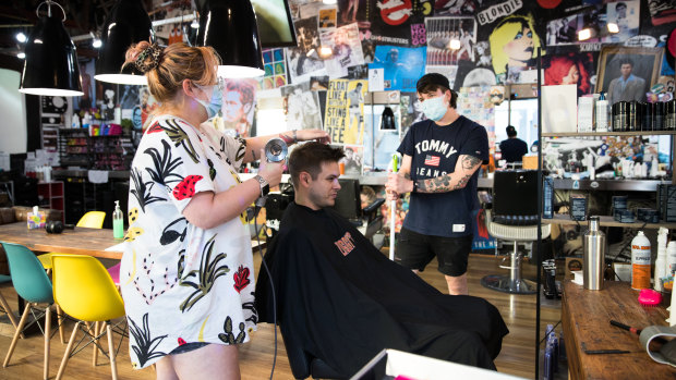 Back open for business: Ziggy Barber Salon's hairdresser Casey Hughes and co-owner Andy Pearson with a client in Surry Hills on Friday.