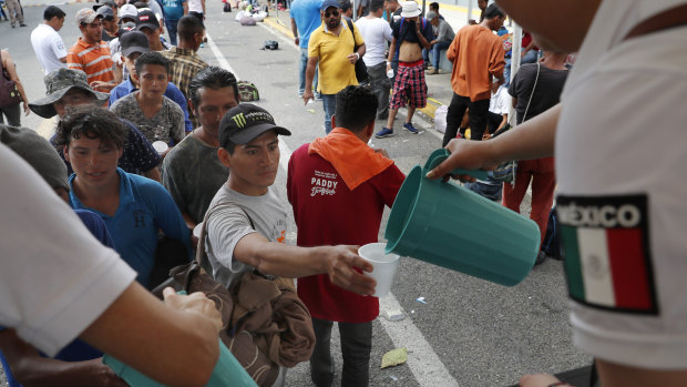 Central American migrants eat lunch, courtesy of Mexican officials, on the border bridge between Mexico and Guatemala.