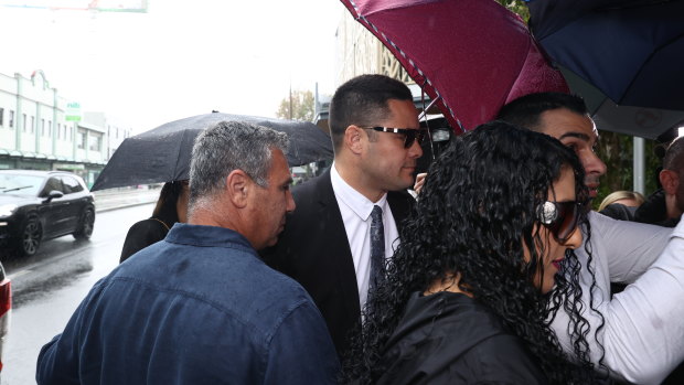 Jarryd Hayne walks into court on Thursday as his supporters attempt to shield him with umbrellas.