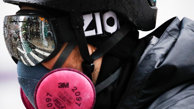 A delivery worker wears personal protective equipment due to COVID-19 concerns while riding a bicycle through the rain outside NYU Langone Medical Centre,