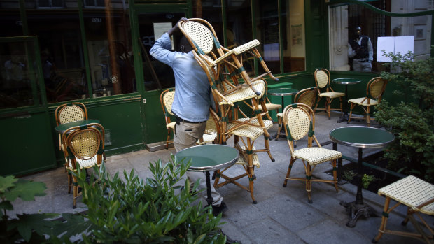 A cafe employee carries chairs as he setting up a terrace in Paris. 