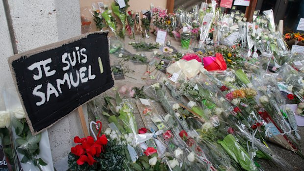 A placard reading "I am Samuel" and flowers lay outside the school where slain history teacher Samuel Paty was working, in Conflans-Sainte-Honorine, north-west of Paris. 