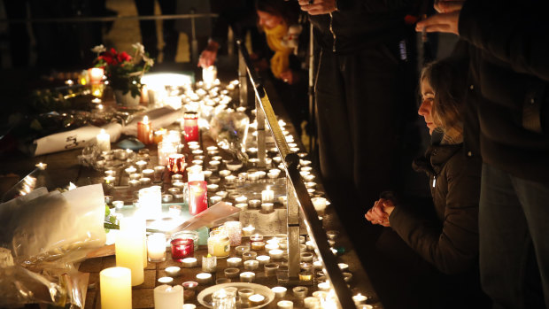 People pay respect and light candles the night following a shooting in Strasbourg, France. 