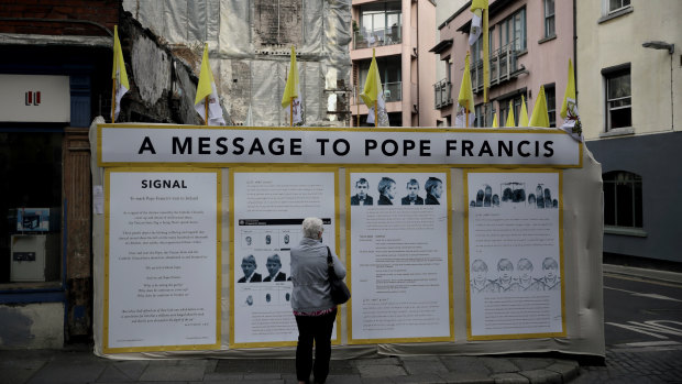 A passerby looks at an art installation by Mannix Flynn protesting the Pope's visit in Dublin, Ireland. 