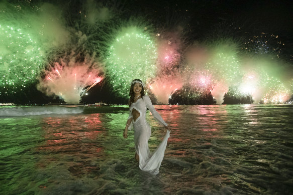 A woman stands as fireworks light up the sky over Copacabana Beach during New Year’s celebrations in Rio de Janeiro.