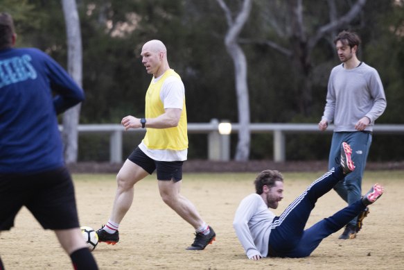 Journalist Angus Thompson slips over as David Pocock dribbles past during a soccer game at Parliament House.