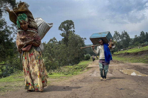 Senait Ambaw, left, who says her home was destroyed in the fighting, carries her belongings out of the town as she looks for a safe place to stay. 