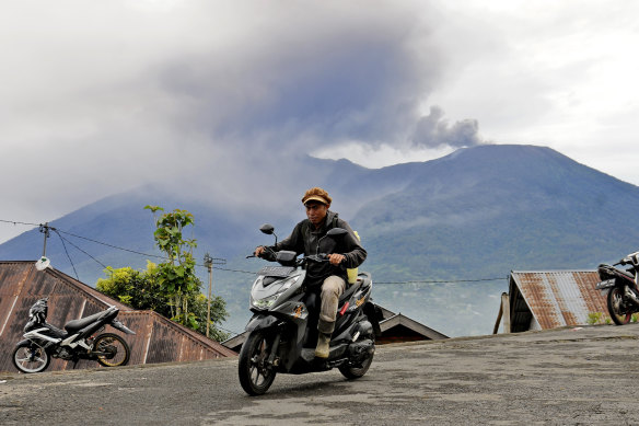 A motorist rides past by as Mount Marapi spews volcanic materials during its eruption in Agam, West Sumatra.