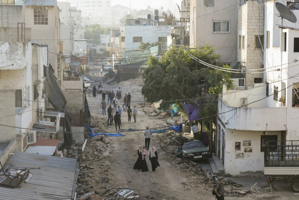 Palestinians walk on a damaged road following two days of an Israeli military raid on the militant stronghold of the Jenin refugee camp.