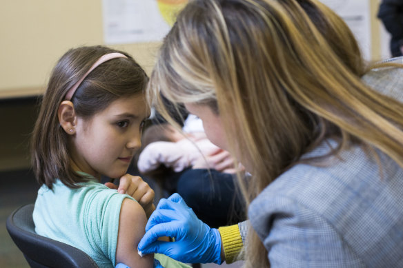 A nine-year-old rolls up her sleeve for a vaccination at a clinic in Portland, Oregon, in February.