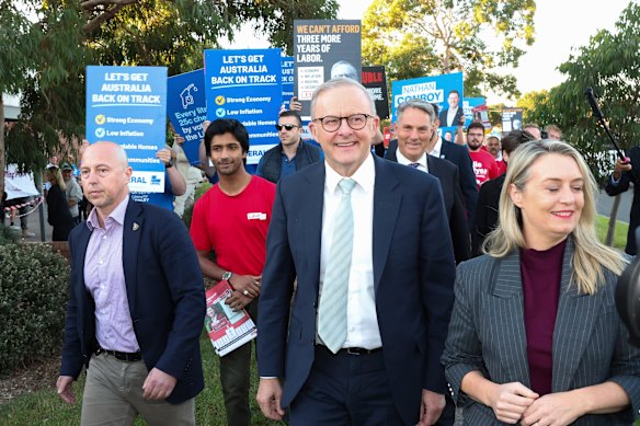 The PM and fiancee Jodie Haydon leave the early polling booth, followed by major parties’ volunteers.