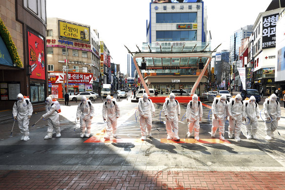South Korean army soldiers wearing protective suits spray disinfectant to prevent the spread of the COVID-19 in Daegu.