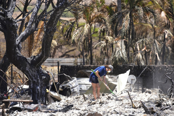 A woman digs through the rubble of a home destroyed by a wildfire in Lahaina, Hawaii, August 11, 2023.