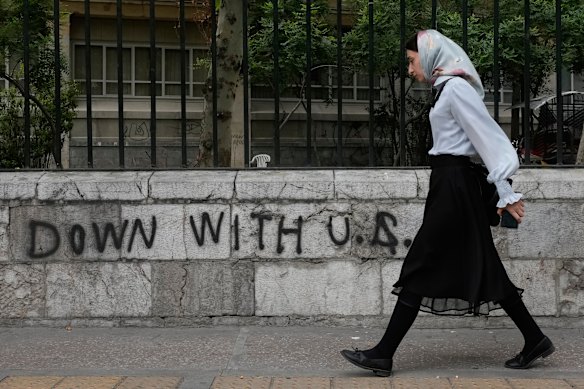 A woman walks past anti-US graffiti on a wall at Tehran University.