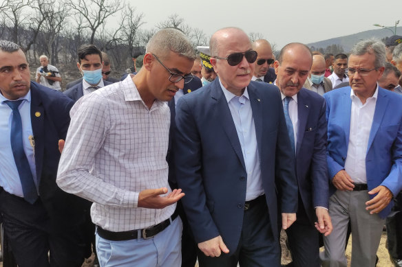 Algerian Prime Minister Aimene Benabderrahmane (centre) visits a village after a wildfire in the region of El Tarf.