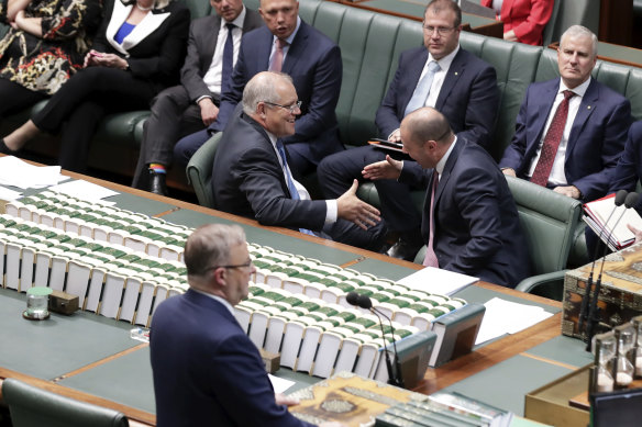 Prime Minister Scott Morrison and Treasurer Josh Frydenberg shake hands after the government’s income tax bill passed the House of Representatives in 2019. But the changes will still mean millions of Australians facing bracket creep.