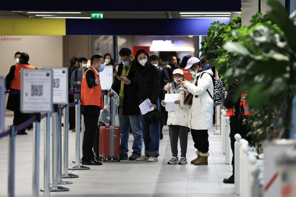 Passengers arriving from China wait in front of a COVID-19 testing area set at the Roissy Charles de Gaulle airport, north of Paris, France.