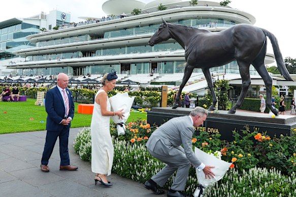 VRC chairman Neil Wilson, chief executive Kylie Rogers and Greg Miles lay flowers.