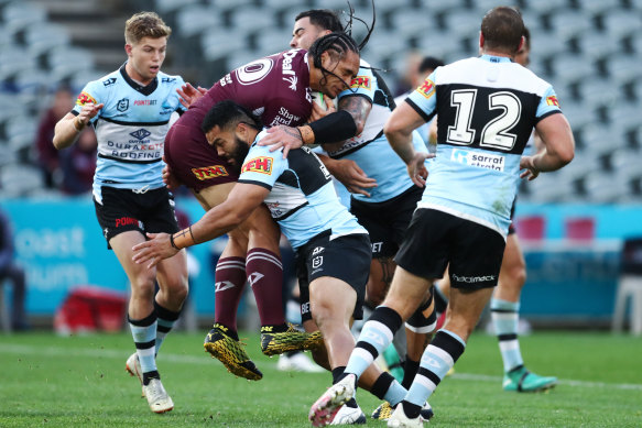 Martin Taupau of the Sea Eagles cops a hit from the Sharks defence.