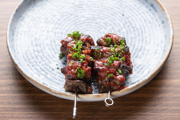 Ox tongue skewers, edges crisp, are glazed with Davidson plum.