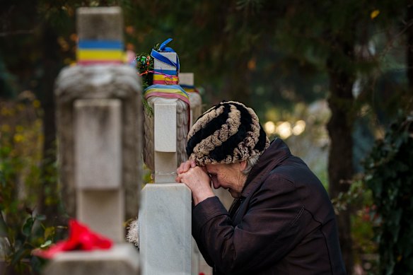 A woman cries leaning on a grave stone during a memorial religious service for those killed in the 1989 anti-communist uprising, in Bucharest, Romania.