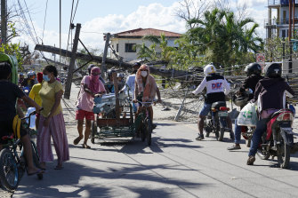 People pass by toppled electrical posts in Cebu province.