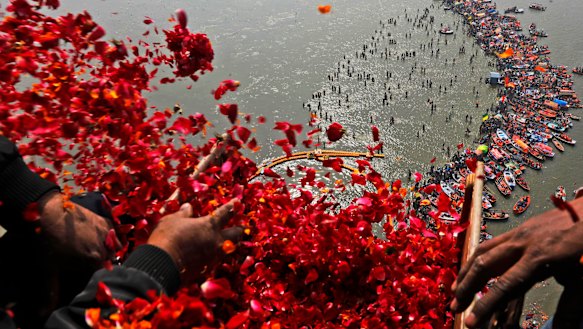 Government officials throw flowers from a helicopter onto thousands of Hindu devotees in the water at Sangam, the confluence of three sacred rivers - the Yamuna, the Ganges and the mythical Saraswati.
