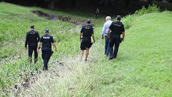 Police search the scene where two bodies were found in a drain running behind the Aitkenvale Library in Townsville. 