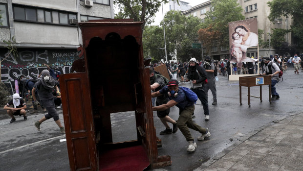 Anti-government protesters drag items from a church to be added to a barricade in Santiago, Chile.
