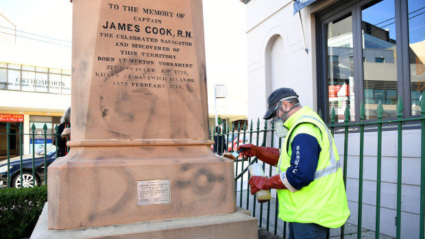 A worker paints over graffiti on a Captain Cook statue in Randwick, Sydney, this week.