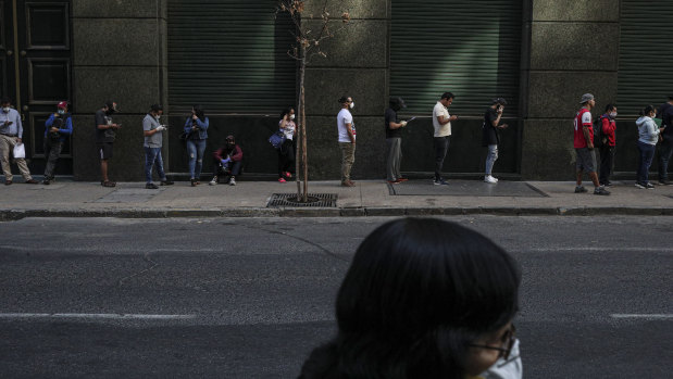 Not just about the money: people wait in line to collect unemployment insurance in Santiago.
