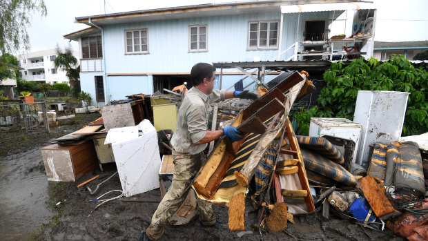 A man helps strangers remove flood-damaged items from their home in the suburb of Rosslea in Townsville on Thursday. 