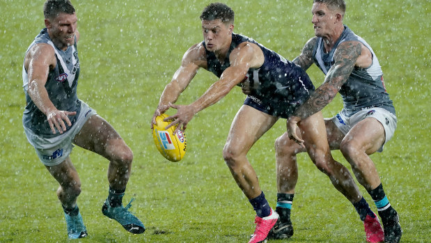Slip and slide: Port Adelaide's Hamish Hartlett tackles Fremantle's Darcy Tucker during a mid-match downpour on the Gold Coast.
