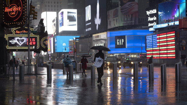 Shoppers walk in a rainstorm through New York's Times Square.