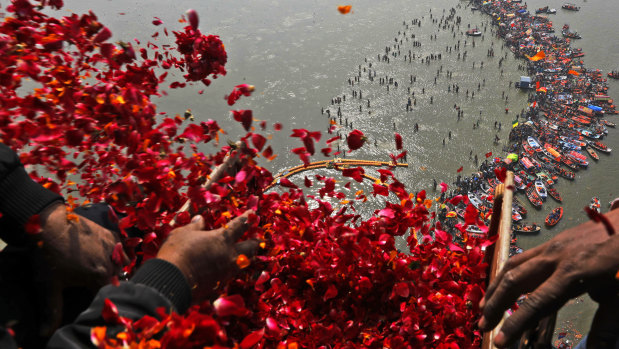 Government officials throw flowers from a helicopter onto thousands of Hindu devotees in the water at Sangam, the confluence of three sacred rivers - the Yamuna, the Ganges and the mythical Saraswati.