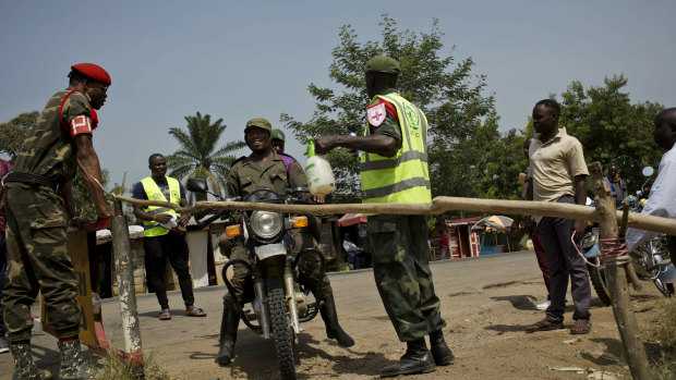 Congolese government soldiers have their feet and motorcycle tyres sprayed with bleach as part of an Ebola containment program on the road between Beni and Oicha, in the DRC.