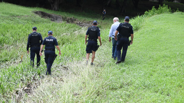 Police search the scene where two bodies were found in a drain running behind the Aitkenvale Library in Townsville. 