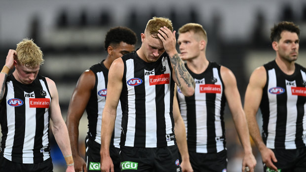 Wings clipped: Jaidyn Stephenson (centre) walks off with his Magpie teammates after Saturday night's loss to the Cats.