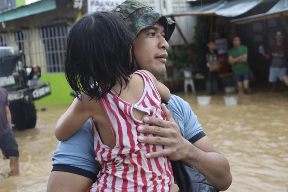 A rescuer carries a child to safer grounds as floods rose due to Tropical Storm Nalgae at Parang, Maguindanao province, southern Philippines.