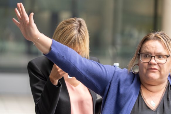 Witness Rebecca Thompson, in black, is shielded by an associate outside the court.