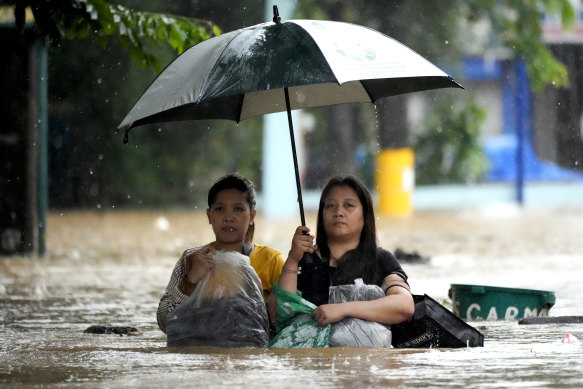 Residents protect their belongings as they negotiate a flooded street caused by heavy rains from Tropical Storm Yagi, locally called Enteng, in Cainta, Rizal province, Philippines.