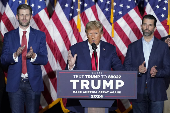 Donald Trump speaks at a caucus night party in Des Moines, Iowa, flanked by sons Eric (left) and Don Jr.