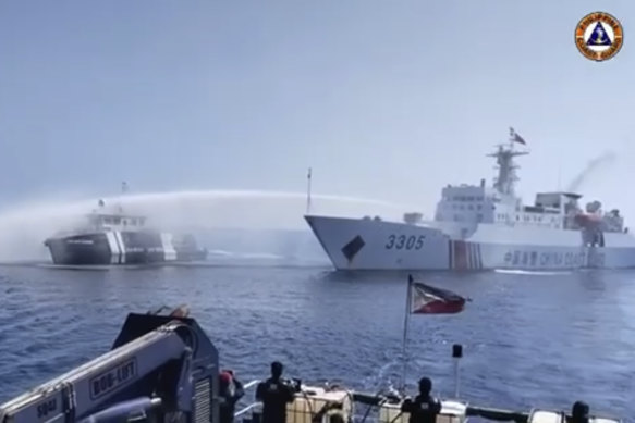In a video still provided by the Philippine Coast Guard, a Chinese Coast Guard ship (right) uses a water cannon on a Philippine Bureau of Fisheries and Aquatic Resources vessel as it approaches Scarborough Shoal on Saturday.