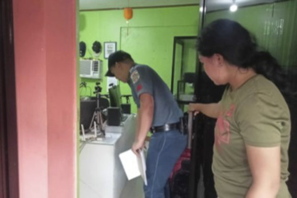 A policeman, left, checks on the area where the radio anchor was fatally shot inside his home-based station in Calamba town in Misamis Occidenta province, southern Philippines.