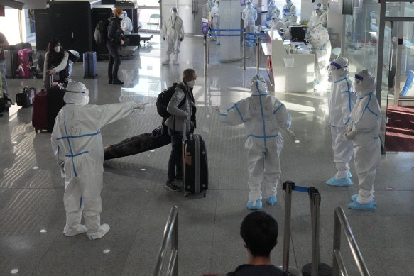Arrival in Beijing: Workers wearing protective suits at the airport assist guests ahead of the 2022 Winter Olympics.