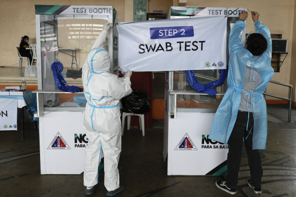 Health workers arrange a sign at a COVID-19 testing site in Quezon City, the Philippines in 2021.