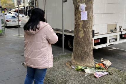 A woman pays her respects at the corner of Bourke and Russell streets this week.